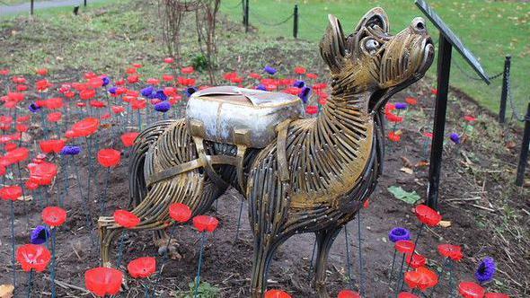 Metal sculpture of Bing seen standing in a flower bed surrounded by red and purple poppies 