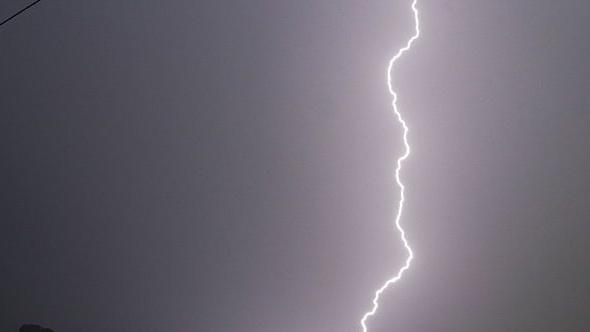 Stock photo of a dark sky with a jagged white line of lightning hitting the ground.