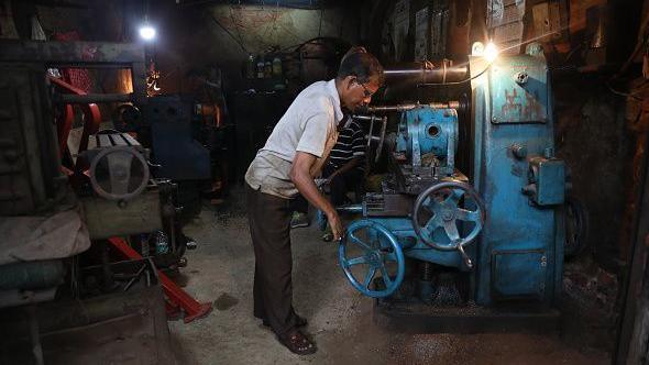 A worker is operating lathes as he is making spare parts of agricultural machines at a manufacturing unit in Kolkata, India, on July 18, 2024. (