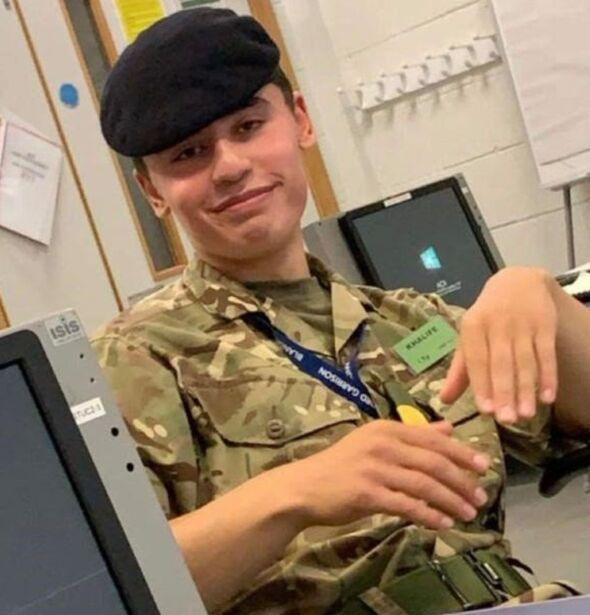 Daniel Khalife pictured wearing a camo army uniform and beret, while wearing a lanyard, looking at the camera and smiling with his hands held out.