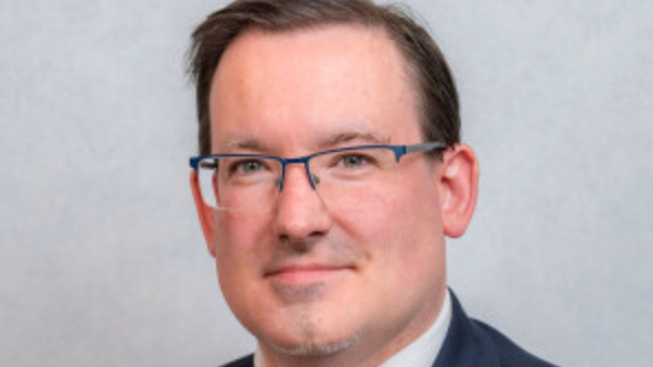 Headshot of Lawrie Hooper - he wears glasses, has short hair and is smiling to the camera.