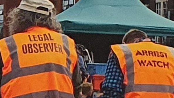 Men wearing tops with the slogan Legal Observers/Arrest Watch on the back