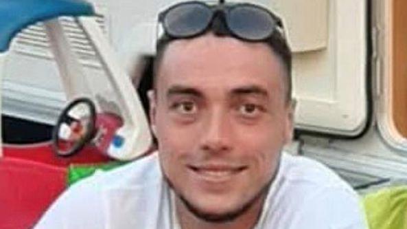 Kieran Shepherd, a man wearing a dark-coloured top with short black hair and a goatee beard. He is sitting down and smiling.