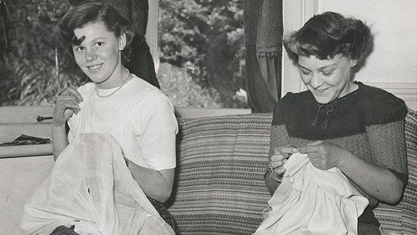 A black and white image of two women sewing.