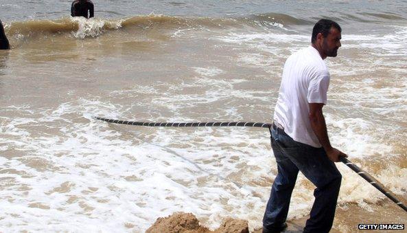 A man pulls an internet cable over the African shoreline