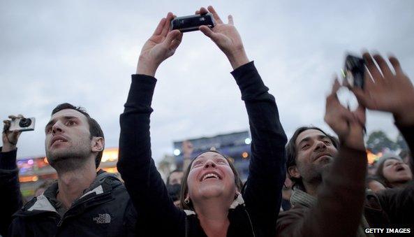 Festival-goers use their mobile phones and cameras to record a Portishead concert