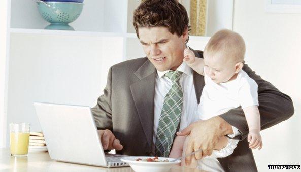 Man working at home, with a baby in his arms