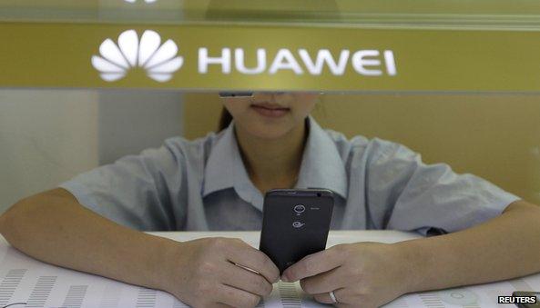 Sales assistant looks at a smartphone in Huawei store