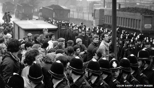 Striking miners watch coal leaving their pit under police guard