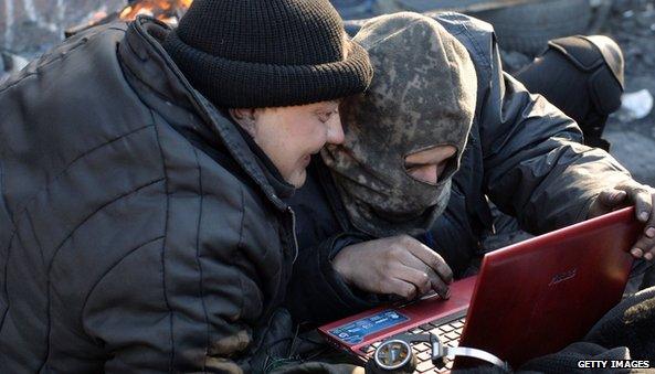 Anti-government protesters read the latest news on internet at a barricade in Kiev