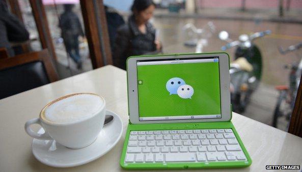 WeChat logo on laptop next to coffee cup