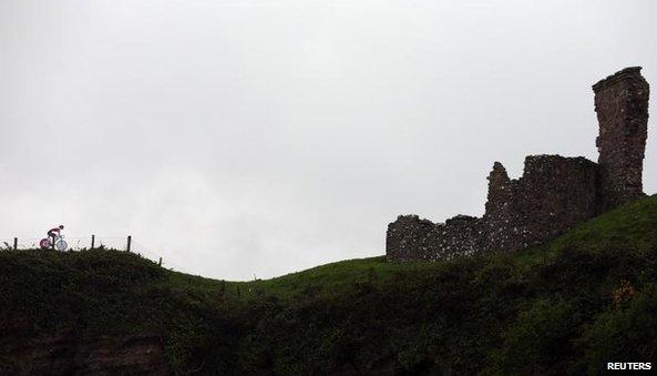 A cardboard cut-out of a bicycle is strapped to a fence beside the ruins of Red Bay Castle