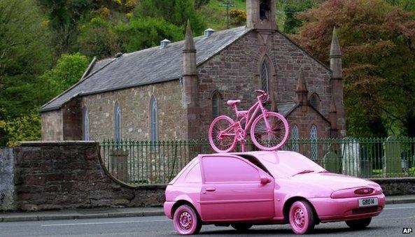 A car and bicycle is painted pink in the village of Cushendall