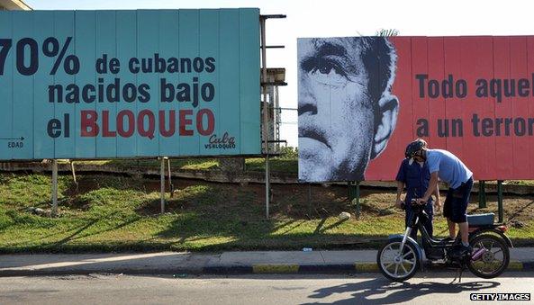 A Cuban checks his motorcycle in front of political billboards allusive to the US embargo on Cuba, on April 20, 2009 in Havana.