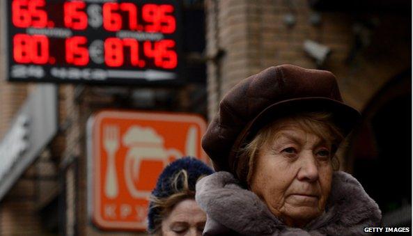 Woman walking in front of exchange rate sign