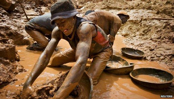 A gold miner scoops mud while digging an open pit at the Chudja mine in the Kilomoto concession near the village of Kobu in this February 23, 2009