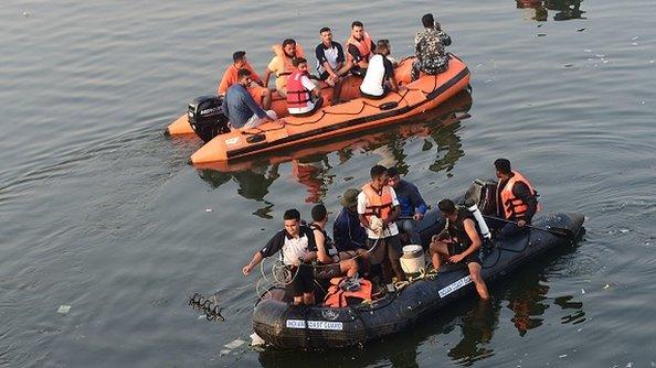 Rescue personnel conduct search operations after a bridge across the river