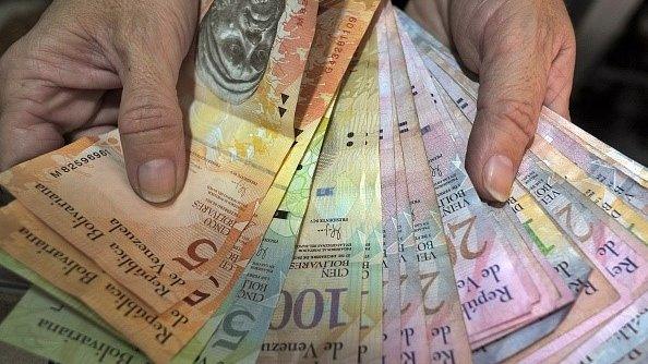 A vendor counts Bolivar notes at her stall in Caracas on February 10, 2015