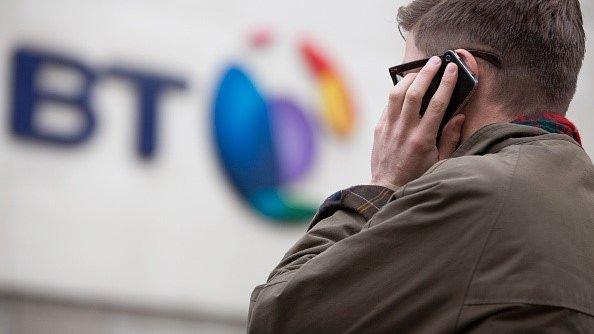 A pedestrian uses a smartphone in this arranged photograph taken outside BT Group Plc's headquarters in London