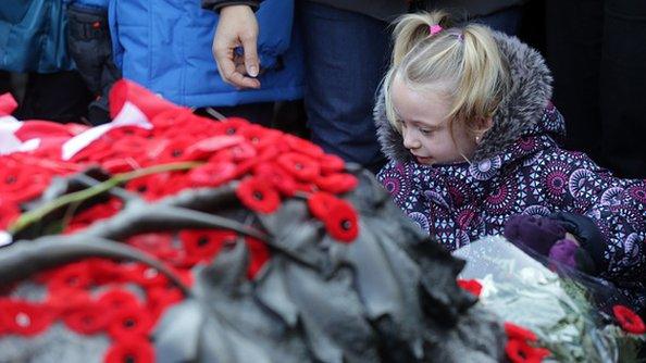 A little girl standing next to poppies.