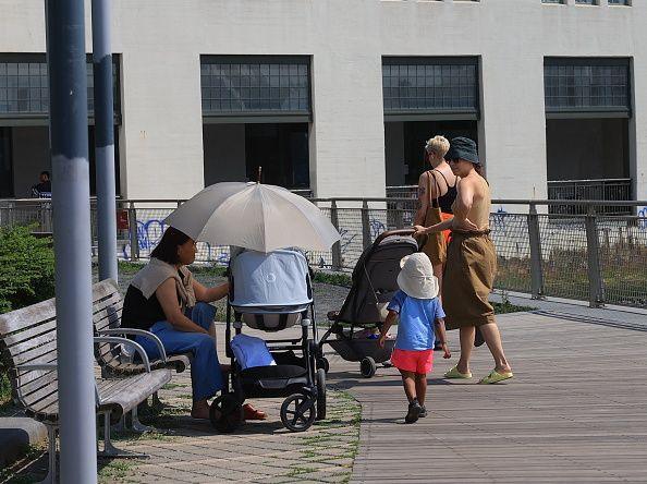 People in a park sheltering under a parasol