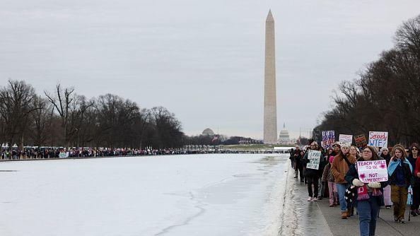 Protesters walk along the National Mall near the Washington Monument