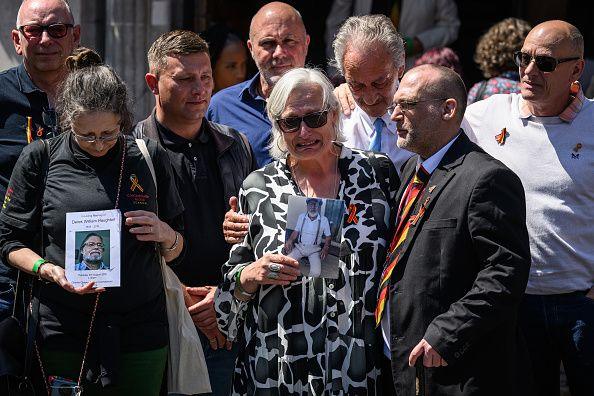 Victims and families stand outside Methodist Central Hall in Westminster holding photographs of their loved ones