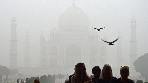 Tourists visit the Taj Mahal on a cold smoggy morning in Agra on November 18, 2024