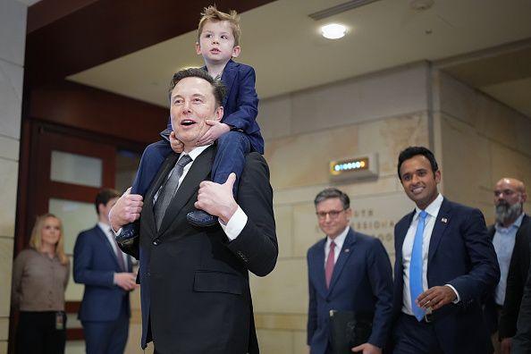 Elon Musk walks through the halls of the US Capitol with a child on his shoulders