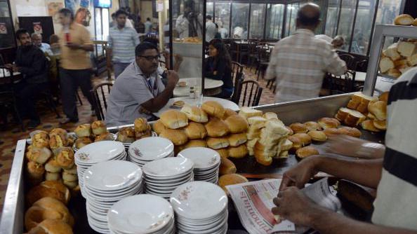 Indian customers wait as an employee packs bun maska - butter buns at the B. Merwan & Co. Irani cafe in Mumbai