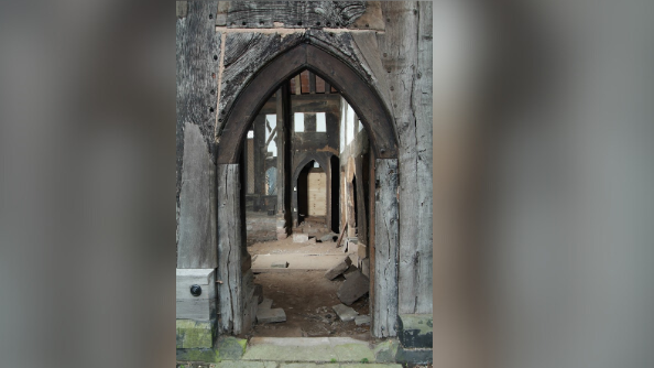A timber and stone archway can be seen but appears to need work done as there are loose bricks on the floor and the general view looks to be in a state of mild disrepair.