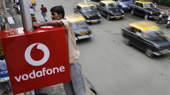 A worker adjusting a Vodafone sign in India