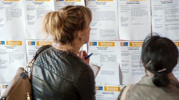 Two women examining advertisements in the job centre