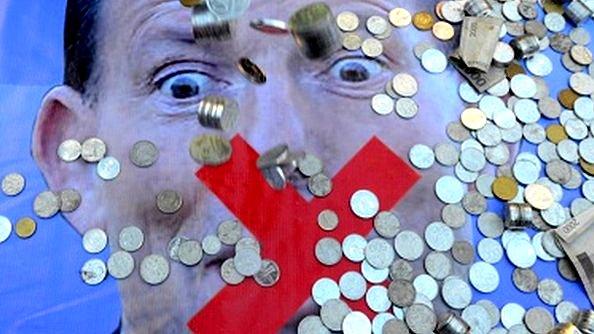 An Indonesian man pours coins from his hands as a 'donation' to Australia's Prime Minister Tony Abbott in Jakarta on 22 February.