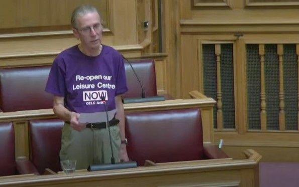 Steve Parlour addressing the council meeting and wearing a purple t-shirt bearing the slogan: Re-open our leisure centre now