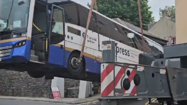 A Translink bus being craned into the air after getting stuck at an intersection in Londonderry