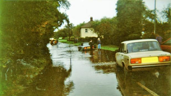 Flooding along a street pictured in the 1980s in a yellowing photograph