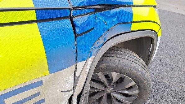 A close up image of a police vehicle shows dents to the front bumper. 