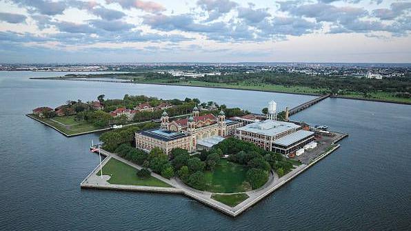 Ellis Island shown from above: the island has a number of buildings, and is joined to the mainland by a bridge.  