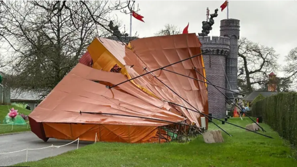 A large structure, which looks like a children's adventure play house at Longleat toppled on its side with a play castle in the background.