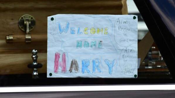 A note reading 'Welcome home Harry' in the hearse of a coffin