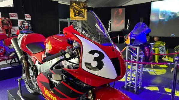A motorbike rider by Joey Dunlop mounted in the middle of the exhibition space. It is red with the number 3 on the front.