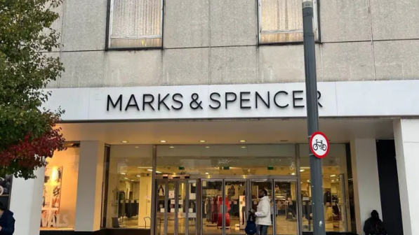 The former Marks and Spencer store in Queensway, Crawley, pictured before it closed for good on 16 November 2024. The front of the shop can be seen with three sets of doors, a person can be seen walking past the set on the right. 