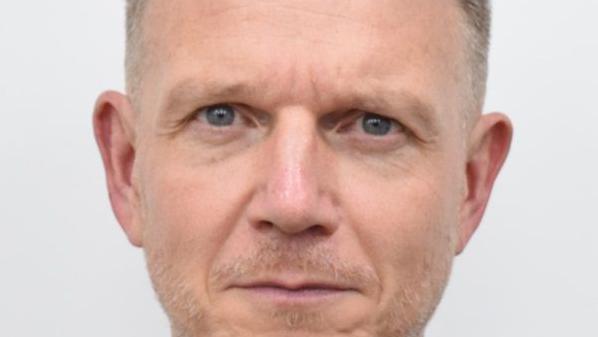 A profile photo of a man with greying hair and dark grey-blue eyes.