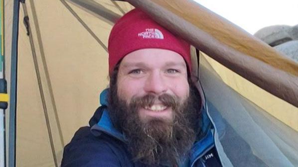 Owen Charnley smiles while poking his head out of a tent