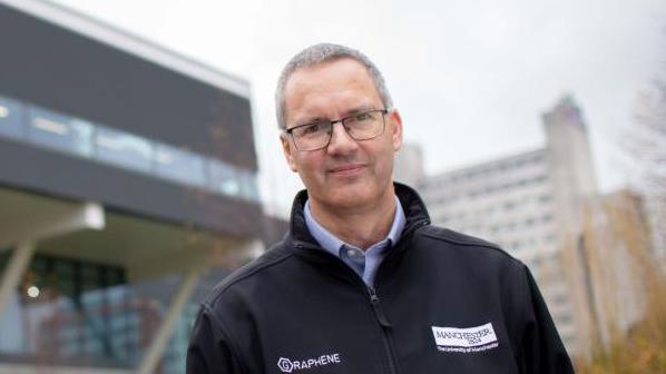 James Baker stands in front of research buildings at the University of Manchester