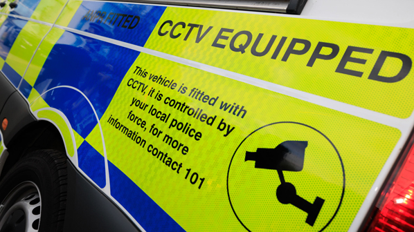 A close-up of the side of a police vehicle. The writing says "CCTV equipped", and "this vehicle is fitted with CCTV, it is controlled by your local police force. For more information contact 101".