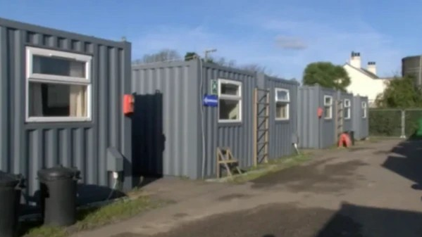 Several grey corrugated iron temporary housing units.