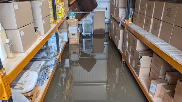 Water on the floor between two shelving units.