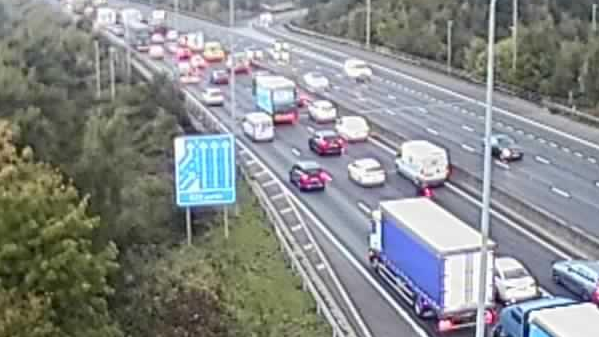Long queues of traffic on the M25 motorway on the carriageway closest to the camera.